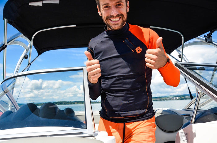 Mann mit Res-T orange zeigt Daumen hoch auf dem Boot