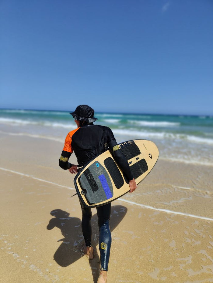 Surfer mit Res-T und Board auf dem Weg ins Meer